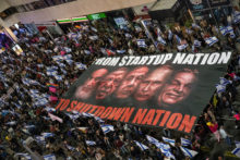 Protesters holding Israeli flags carry a giant banner with